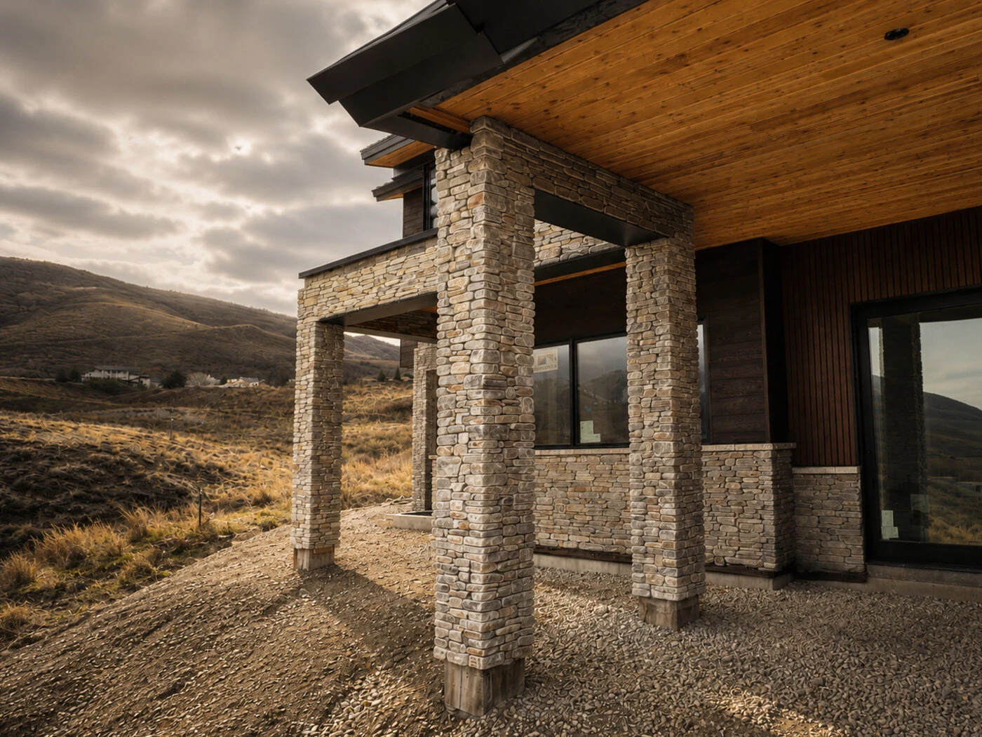 After: covered patio with dry-stack stone columns, cedar soffit ceiling and dark vertical siding