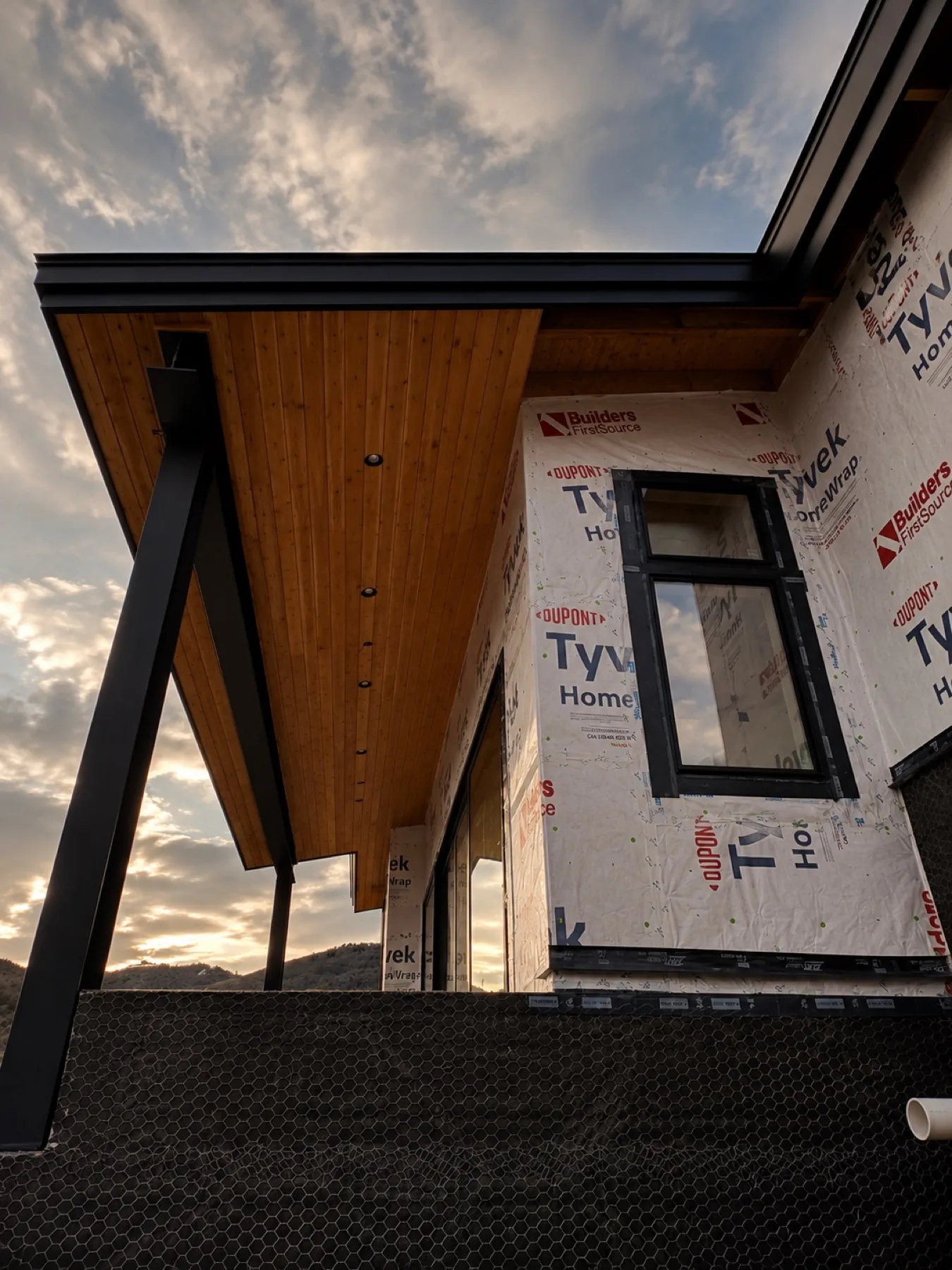 Cedar soffit and black steel detail under construction at sunset
