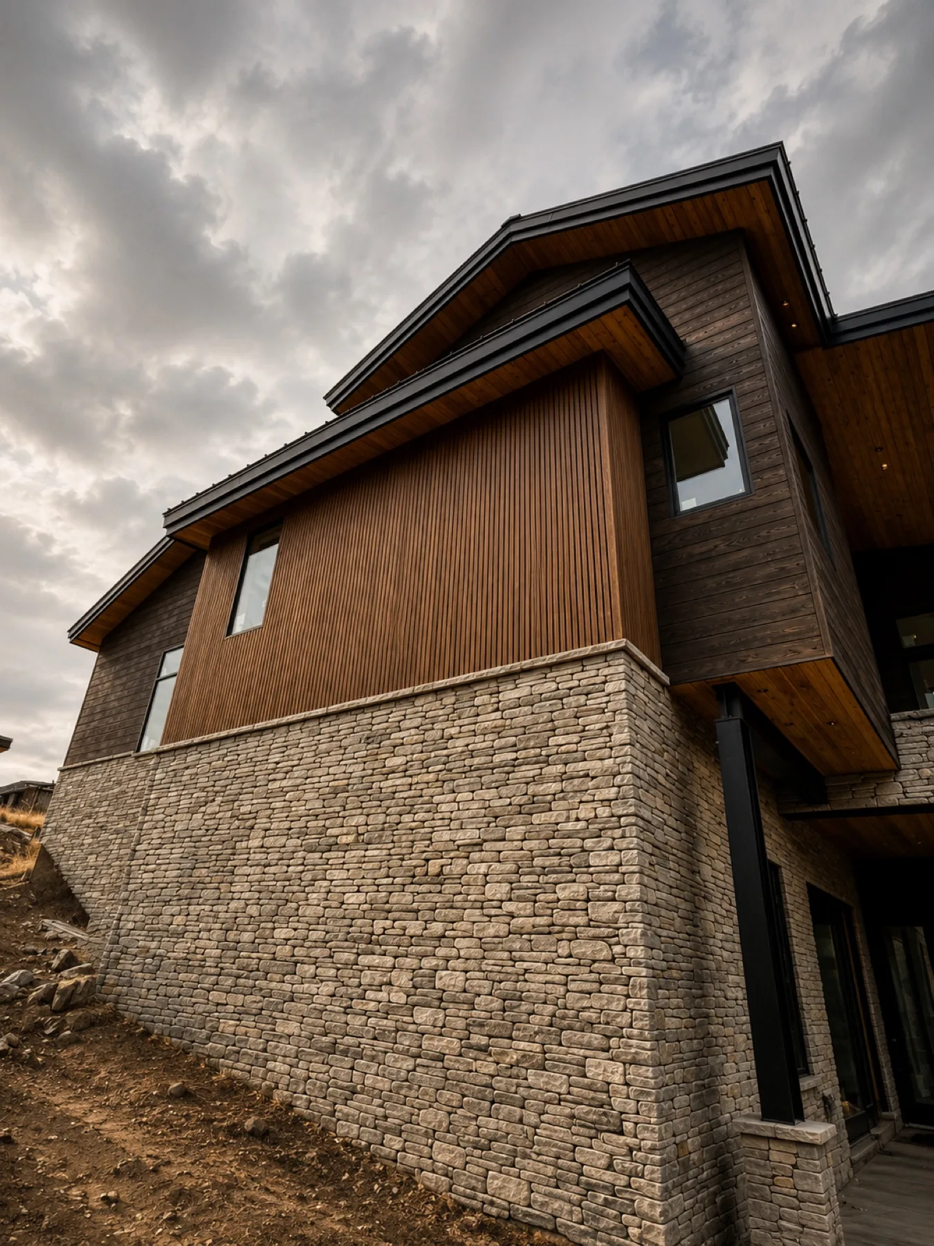 Vertical cedar siding and dry-stack stone veneer installation on a hillside home in Utah County
