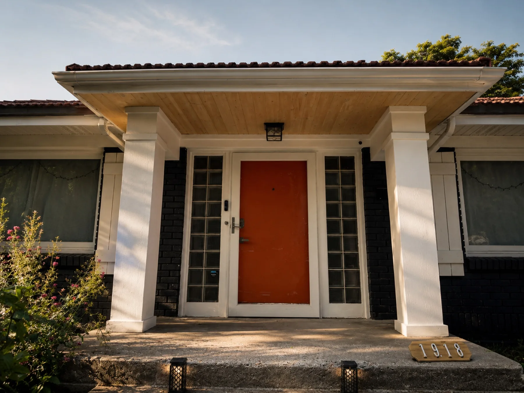 Refinished front porch with white columns, wood ceiling and orange door